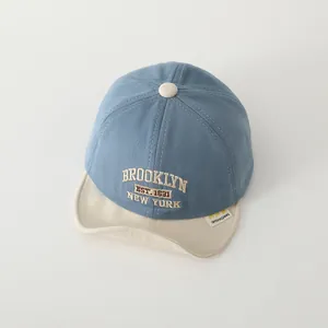 Dettaglio del ricamo Brooklyn sul berretto da baseball bicolore per neonati con visiera morbida