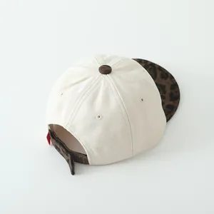 Détail d'une casquette bébé avec tissu crème et sangle réglable à imprimé léopard