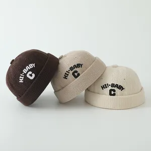 Détail de trois bonnets tricotés pour bébé avec broderie lettre C en tons terre