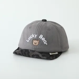 Détail de la broderie Lucky Bear et visière léopard sur une casquette grise bébé