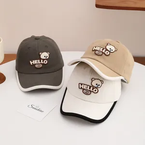 Detailed close-up of cartoon bear embroidery and HELLO lettering on cotton baseball caps