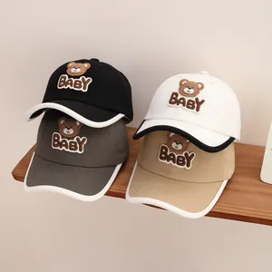 Close-up of baby baseball caps with plush bear patches and BABY embroidery in four colors