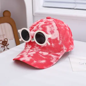 Detail of red tie-dye kids baseball cap with decorative white round sunglasses attached