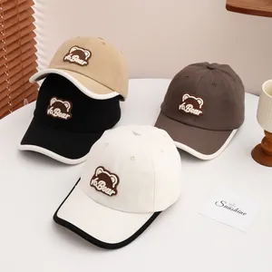 Detailed view of kids cartoon bear embroidery on cotton canvas baseball caps in various colors