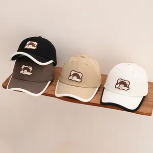 Detail of four cartoon bear baseball caps in black, grey, beige and white on a shelf