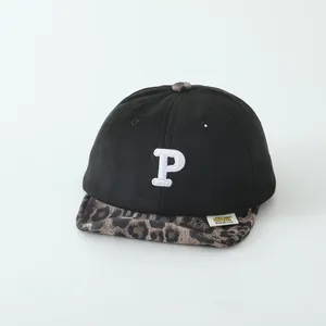 Detail of baby baseball cap with white P letter embroidery and leopard print brim