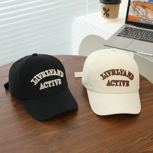 Black and beige cotton kids baseball caps with Lively and Active embroidery on a table