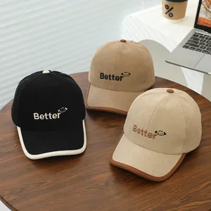 Three corduroy baseball caps with Better embroidery and smile icons on a wooden table