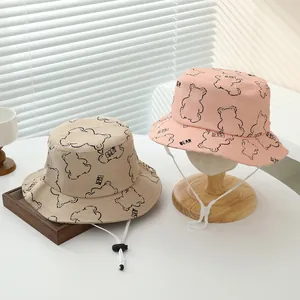 Detalle de gorros de pescador infantiles rosa y beige con estampado de oso y cordón ajustable