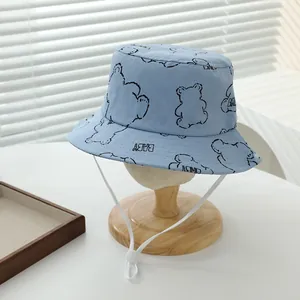 Detalle de gorro de sol para bebé en algodón azul claro con oso y cordón ajustable