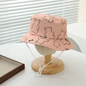 Detalle de gorro de pescador rosa para niños con dibujos de osos y cordón ajustable blanco