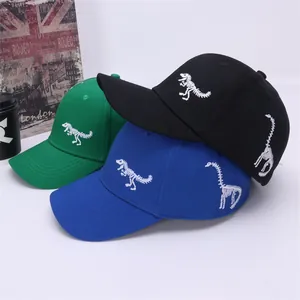 Detail showing dinosaur skeleton embroidery on green, blue, and black cotton baseball caps