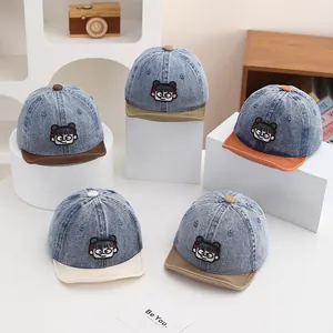 Detail of assorted denim baby baseball caps with cartoon embroidery and color-block brims