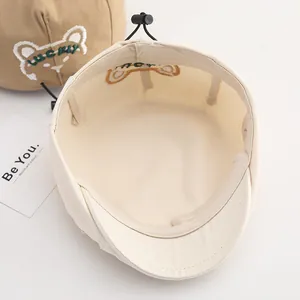 Dettaglio del cordoncino regolabile e del ricamo sul cappellino in cotone per bambini