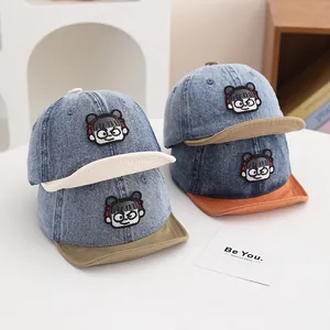 Detail of children's denim baseball caps with cartoon embroidery and contrast color brims