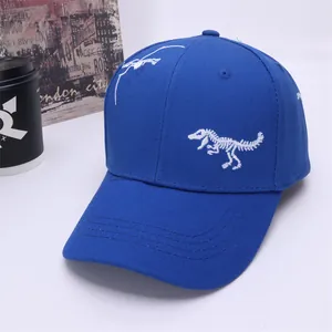 Detail of white dinosaur skeleton embroidery on a blue cotton canvas baseball cap