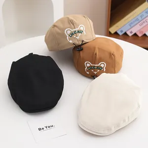 Dettaglio di quattro baschi retrò per bambini in nero e beige con ricamo di orso fortunato