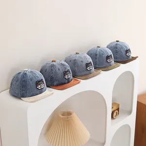 Detail view of colorful denim baseball caps with cartoon embroidery and contrast brims
