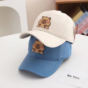 Détail de patchs capybara mignons sur des casquettes en coton beige et bleu pour enfants