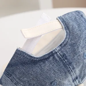 Detail view of denim baseball cap with adjustable strap and textured stitching