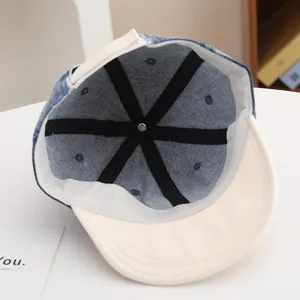 Detailed interior of color-block denim baby cap showing six-panel stitching and velcro strap