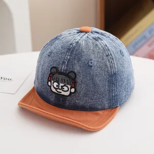 Detail of blue denim baby baseball cap with orange brim and cute girl embroidery