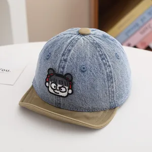 Close-up of baby denim baseball cap featuring cartoon embroidery and brown visor