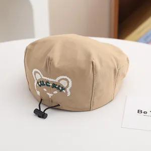 Dettaglio del berretto kaki per bambini con ricamo a orsetto e cordino regolabile