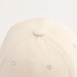Macro view of cream cotton bucket hat showing embroidered eyelets and stitching details