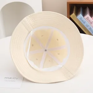 Detail view of cream cotton bucket hat interior showing white sweatband and stitching