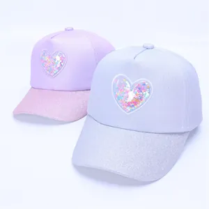 Close-up of kids baseball caps featuring glitter brims and sequin heart pockets