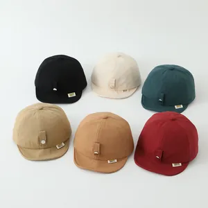 Vista piatta di cappellini da baseball morbidi per bambini in sei colori con bottoni decorativi
