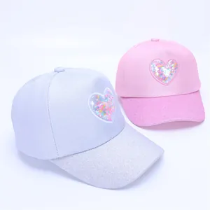 Detailed view of glitter baseball caps with sequin heart patches and shiny brim for girls
