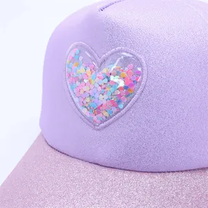 Close-up of glittery purple baseball cap featuring a transparent heart filled with sequins