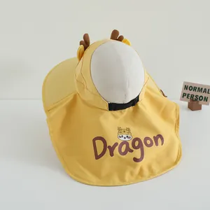 Detail of yellow kids sun hat with neck flap, cartoon dragon horns and cute print