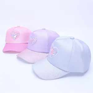 Detail of children's baseball caps with glittery heart patches and shimmering brims