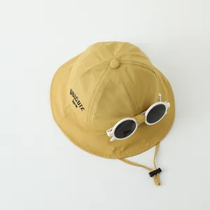 Detalle de gorro de pescador amarillo para niños con cuerda ajustable y estampado