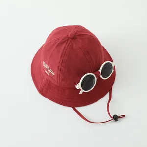Detailaufnahme roter Kinder-Fischerhut mit Deko-Sonnenbrille und weißem Stickmotiv