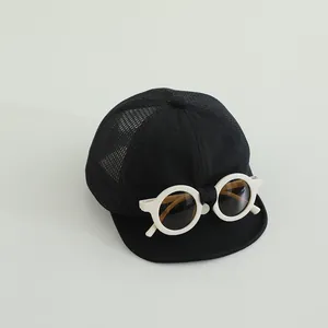 Dettaglio cappellino bebè con occhiali da sole bianchi e rete nera traspirante