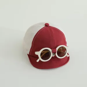 Dettaglio del cappellino neonato in rete con occhiali decorativi e visiera rossa