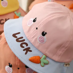 Pastel pink and blue baby sun hat with cute cartoon face and carrot 3D detail