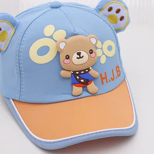 Détail d'une casquette filet bébé avec patch ours 3D et oreilles brodées sur fond bleu