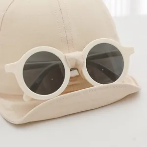 Close-up of beige cotton baby baseball cap with unique white round frame sunglasses