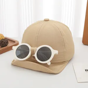Detail view of khaki cotton baby baseball cap featuring detachable white round sunglasses