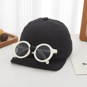 Detail of a kids black baseball cap featuring decorative white round frame sunglasses on top