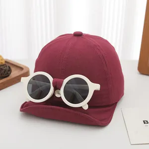 Detail of burgundy kids baseball cap with unique white round sunglasses decoration