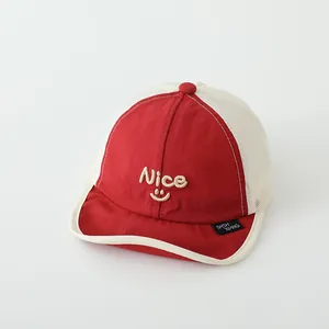 Detail der rot-cremefarbenen Baby-Netz-Baseballkappe mit besticktem Nice-Smiley-Logo