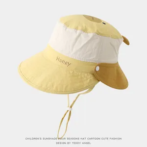 Detail of yellow and beige baby sun hat featuring cartoon bear and Honey embroidery