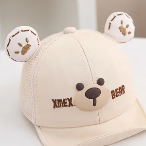 Vista de detalle de la gorra de malla para bebé beige con orejas 3D y parche de oso
