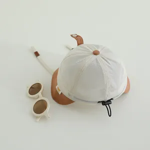 Dettaglio cappello parasole bimbo in mesh bianco con tesa marrone e cinturino
